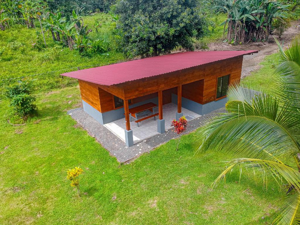 a small building with a red roof in a field at Cabaña Ecos del Río in Jabillos