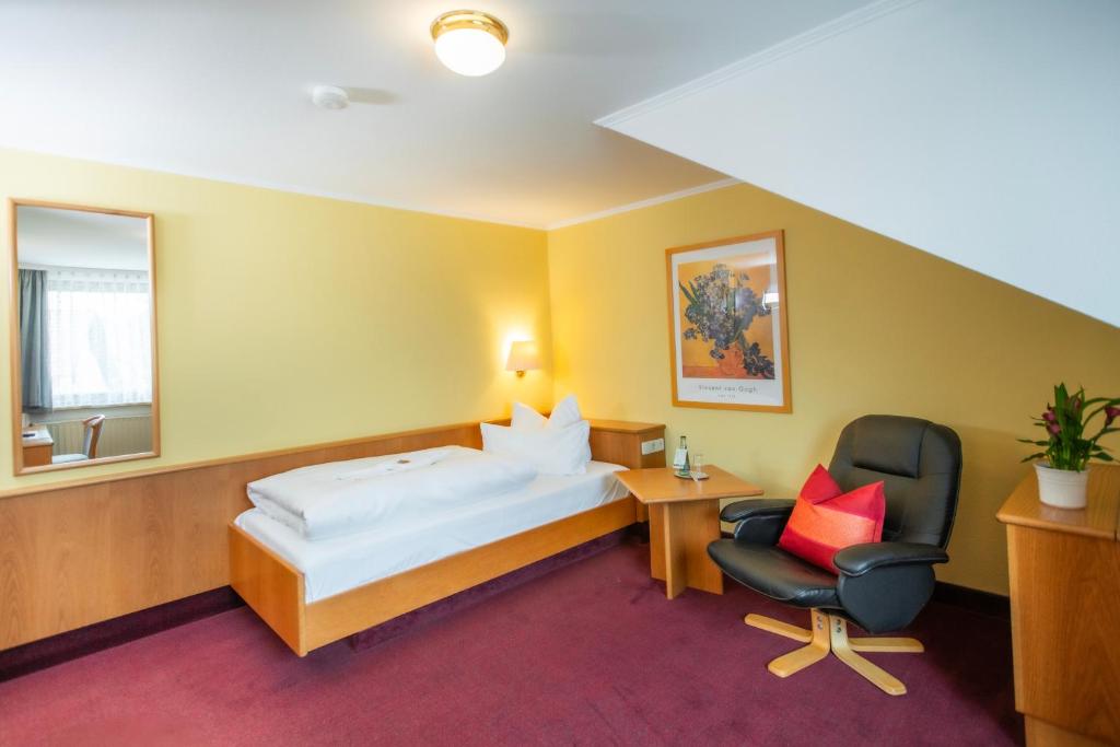 a hotel room with a bed and a chair at Landhotel Plauen - Gasthof Zwoschwitz in Plauen
