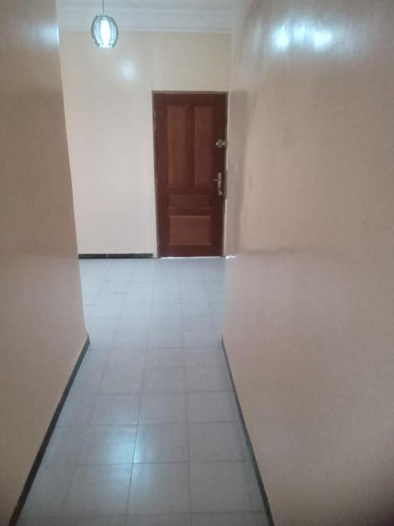 une pièce vide avec une porte et un sol en carrelage blanc dans l'établissement Hébergement 4 pièces Dakar, à Darou Rhamane