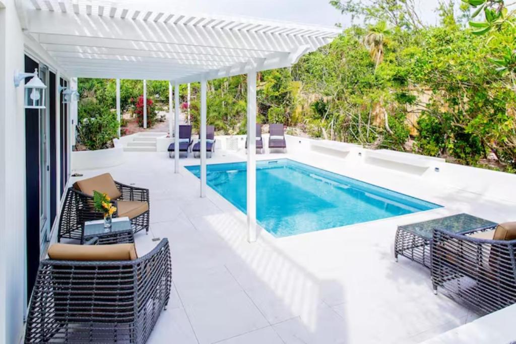 un patio extérieur avec une piscine et une pergola blanche dans l'établissement Esencia Premiere, à Providenciales
