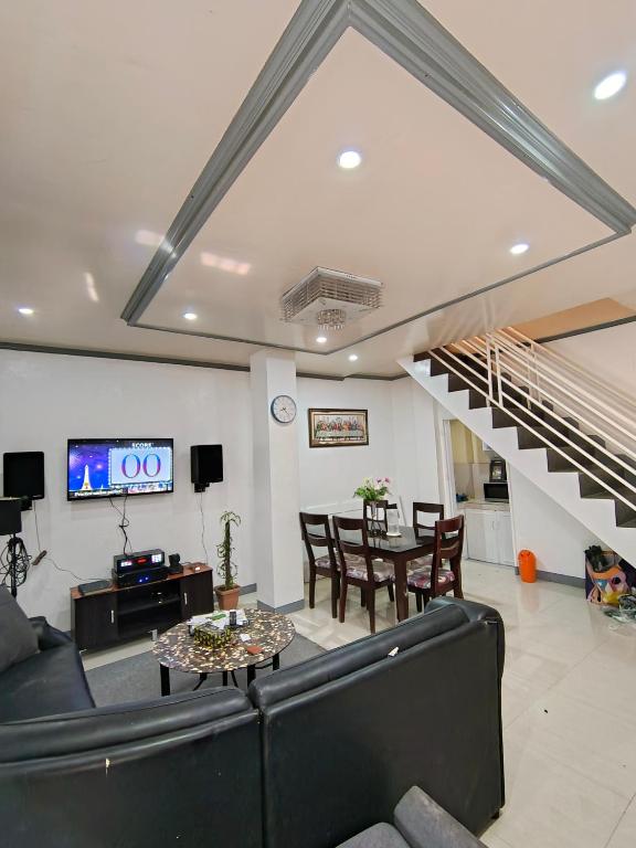 a living room with a black couch and a staircase at Transient in Davao City