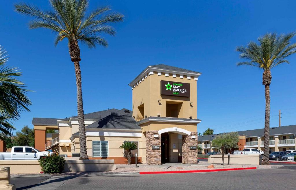 a hotel with palm trees in front of a building at Extended Stay America Select Suites - Phoenix - Airport - E Oak St in Phoenix