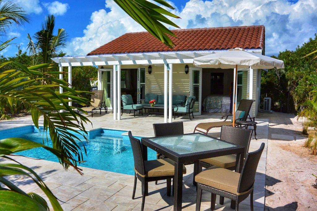 a patio with a table and chairs next to a pool at Esencia Cottage in Providenciales