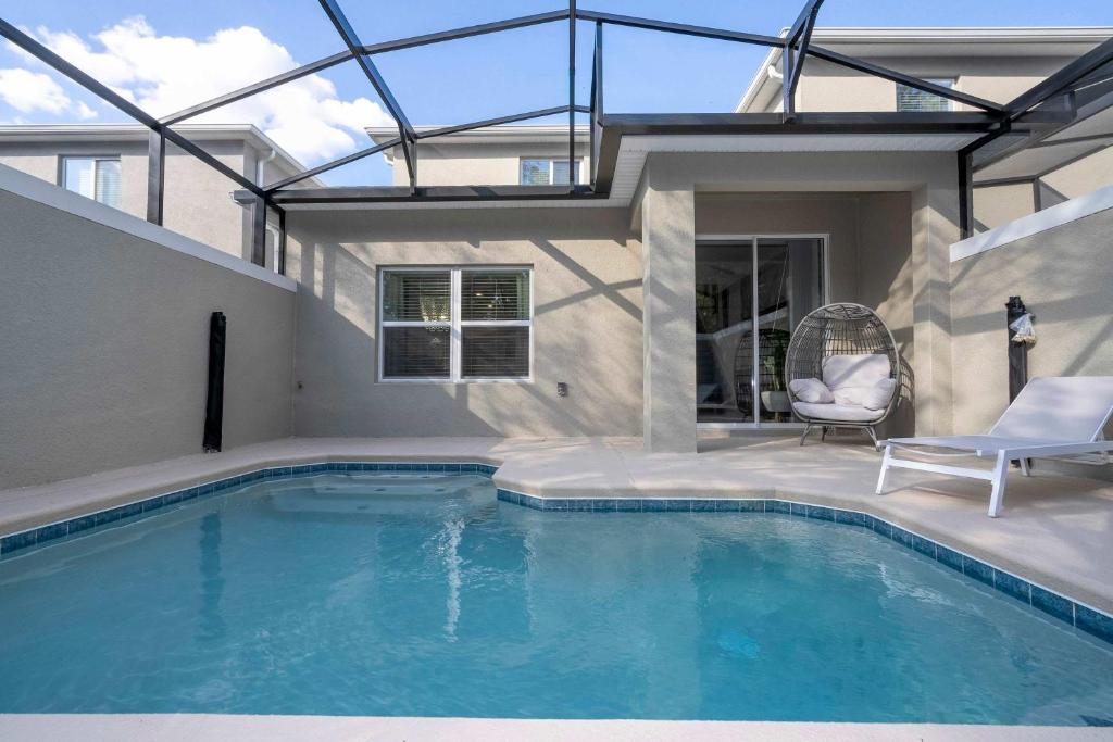 a swimming pool with a chair next to a house at NEW to Market 5 Bed - Storey Lake Retreat in Kissimmee