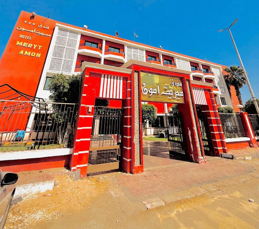 an orange and white building with a red door at فندق ميريت امون سوهاج in Jazīrat Maḩrūs