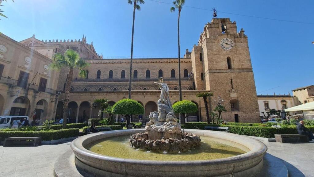 una fuente frente a un edificio con una torre de reloj en Casetta al Duomo, en Monreale
