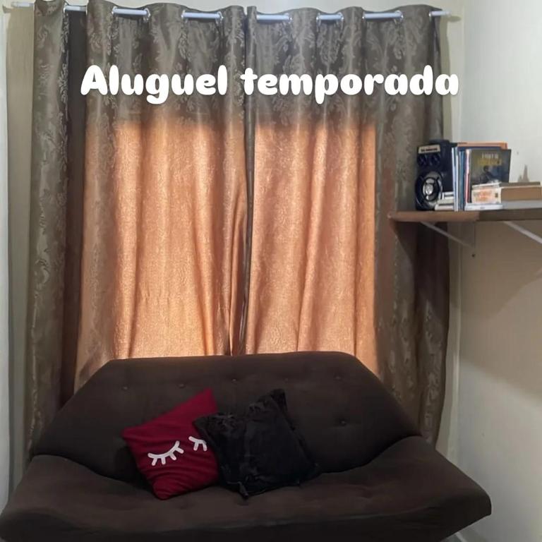 a couch sitting in front of a window with an annoyed tempretoria sign at Casa sobrado in Arraial do Cabo