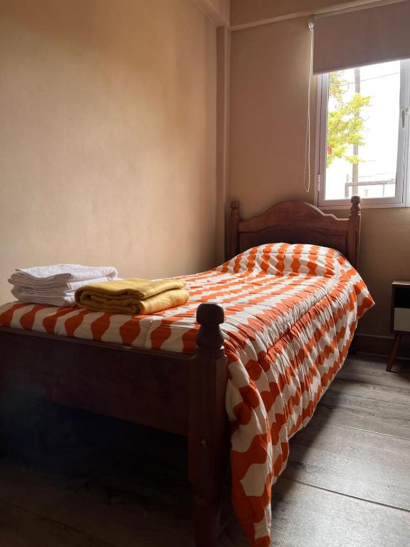 a bed with an orange and white blanket on it at Paihuen in Plottier