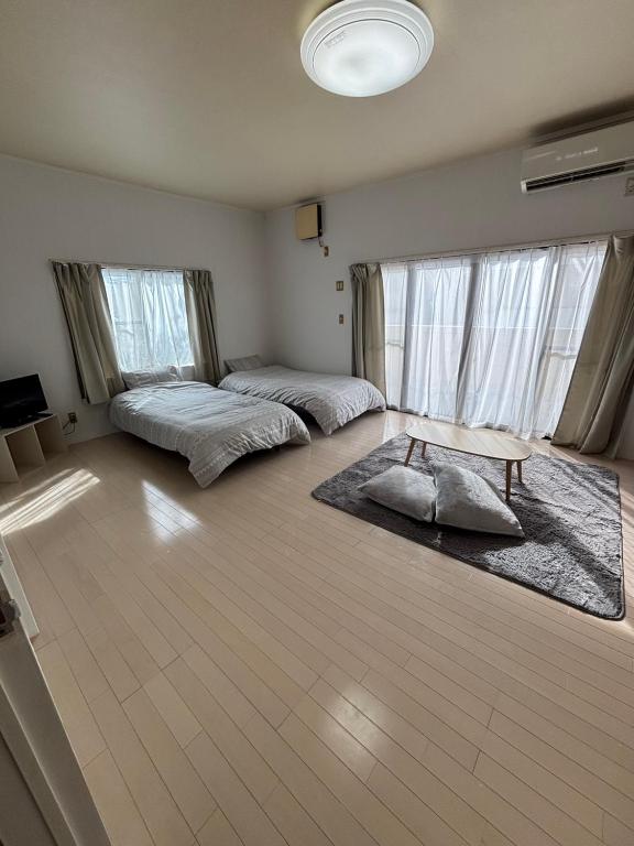 a bedroom with two beds and a table in it at ゲストハウスharu in Shingū