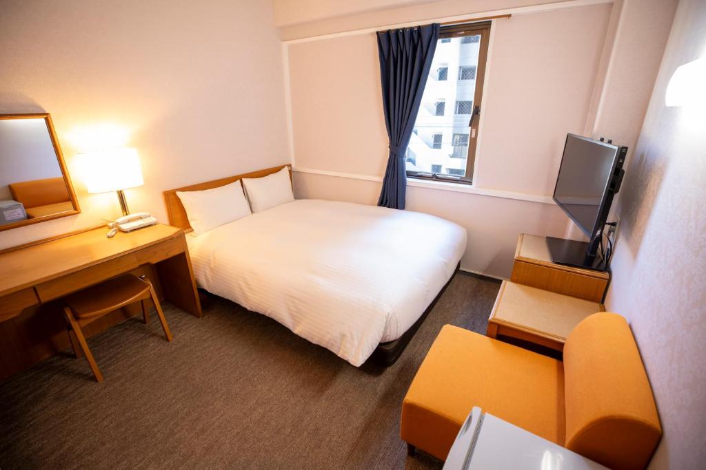 a small hotel room with a bed and a desk at Hotel New Saitama in Saitama