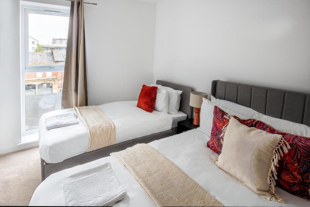 a bedroom with two beds and a large window at Modern Downtown Gem- Brand New Apartments on Cannon St in Preston