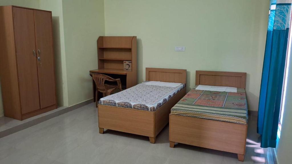 two twin beds in a room with a desk at Riddhi Homestay in Dahmi