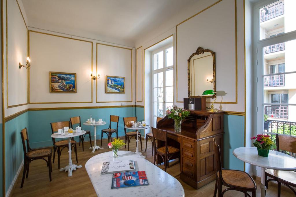 a restaurant with tables and chairs and a mirror at Hôtel Richelieu in Menton