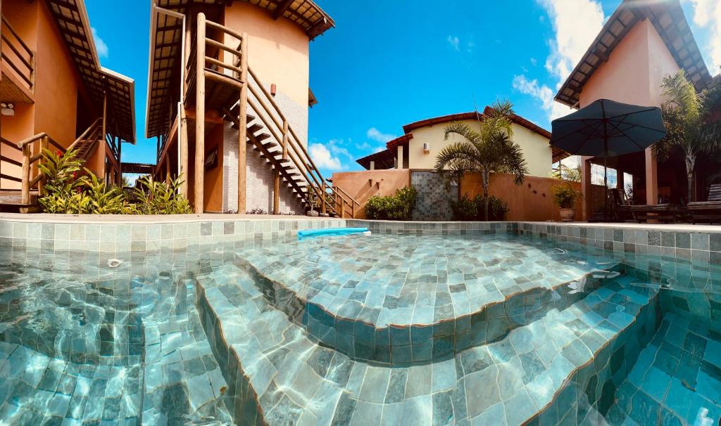 una piscina di fronte a un edificio con ombrellone di Pousada Vila dos Corais - Taipu de Fora a Barra Grande