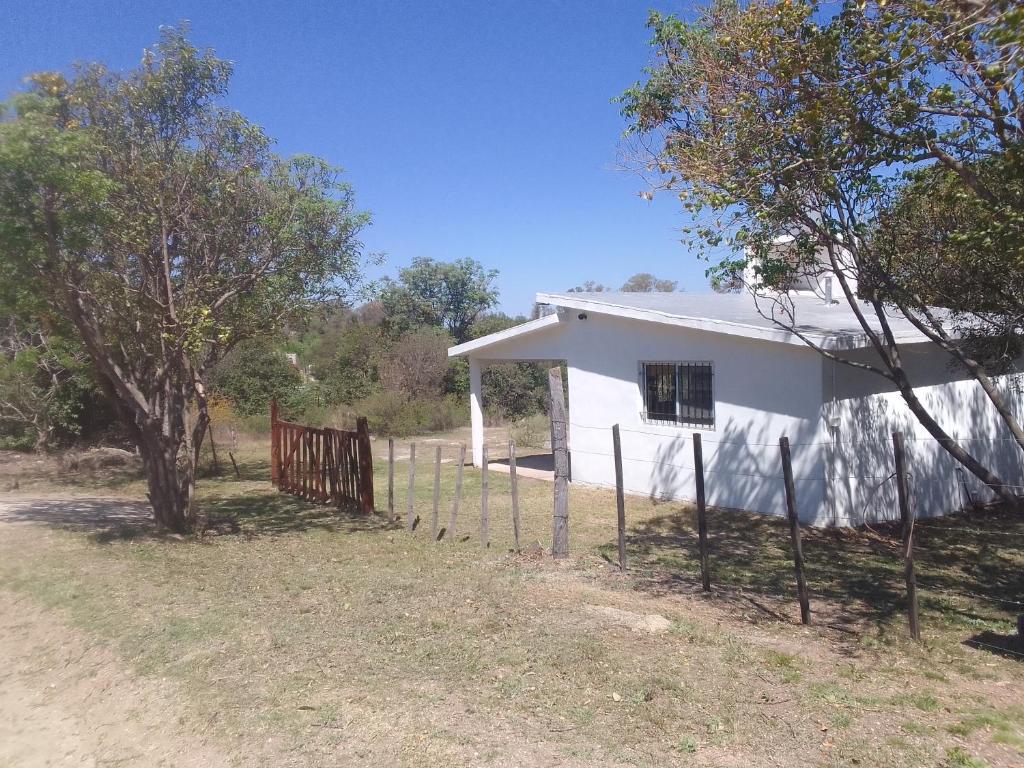 une maison blanche avec une clôture devant dans l'établissement Monoambiente El Arcano, à Tanti