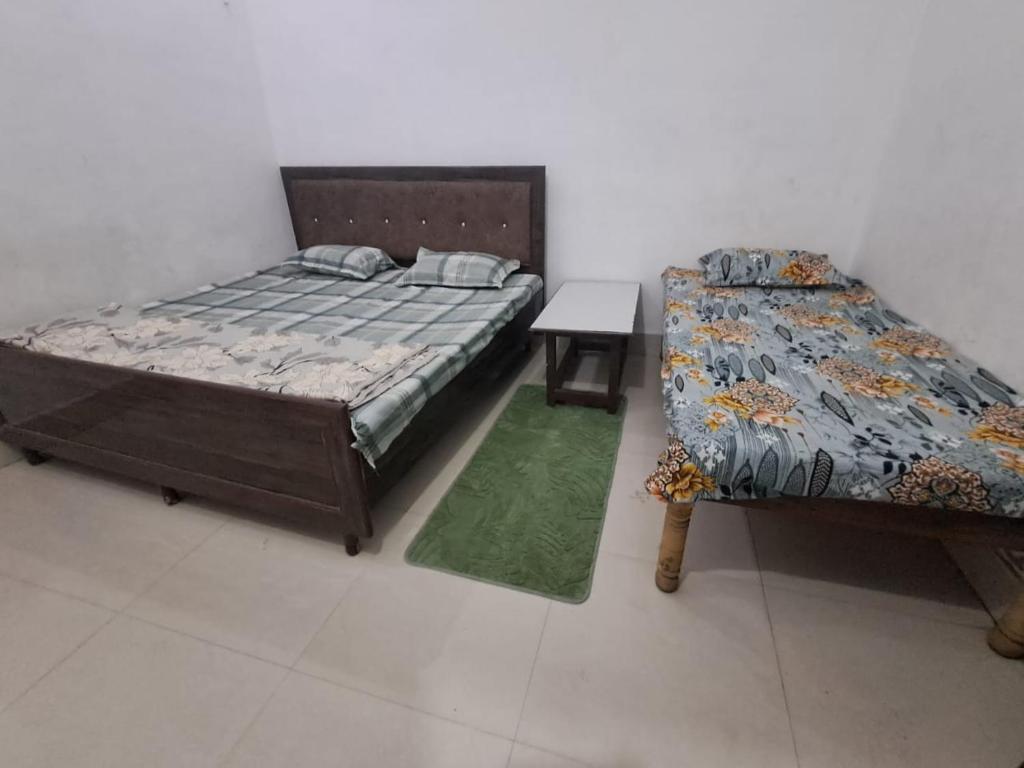 a bedroom with two beds and a table in it at Vrindavan Homestay in Vrindāvan