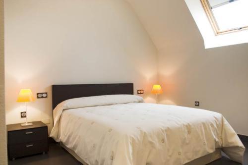 um quarto com uma cama branca e 2 candeeiros em Archybal Apartamentos Turísticos y Suites em Archena