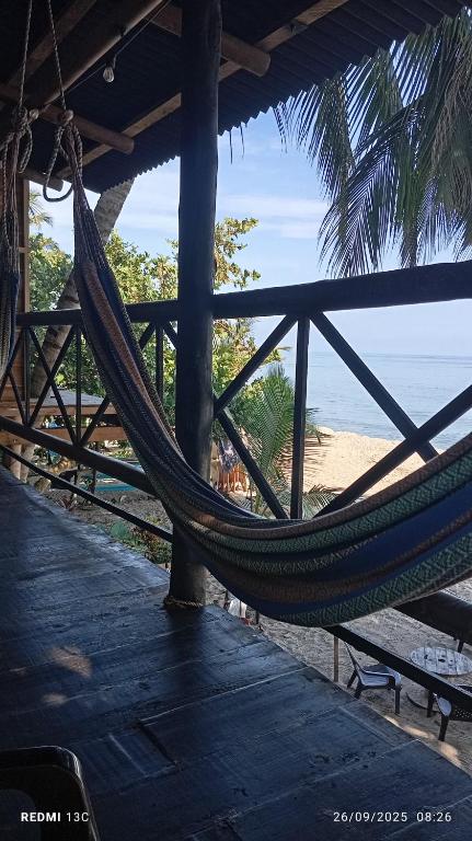 a hammock hanging from a building on a beach at HOSTAL Estrellas del tayrona playa mendihuaca in Santa Marta