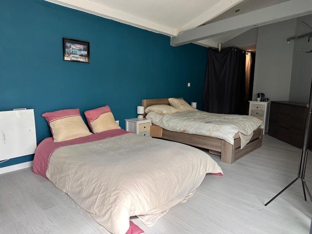 a bedroom with two beds and a blue wall at Chambre pour 4 personnes avec SdB privative et jacuzzi in Le Petit-Couronne