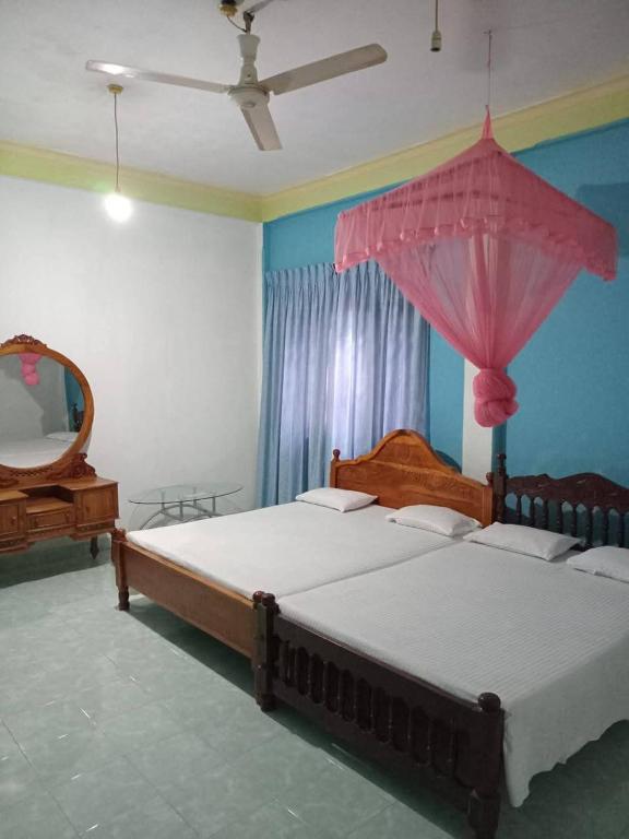 a bedroom with two beds and a pink umbrella at Ranmini Family Resort in Anuradhapura