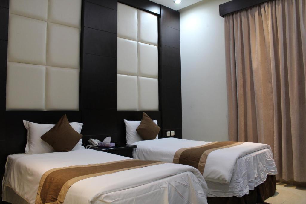 Dana Park في الرياض: سريرين في غرفة الفندق بيضاء وبنية