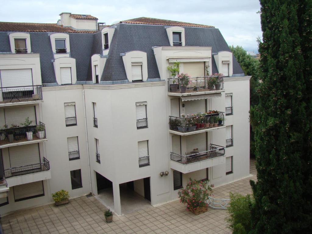 a white apartment building with balconies and a gray roof at Le Turenne in Bordeaux