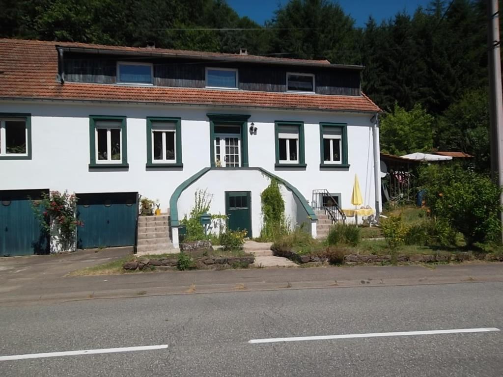 a white house with a green door on a street at Fewo Reyersviller in Reyersviller