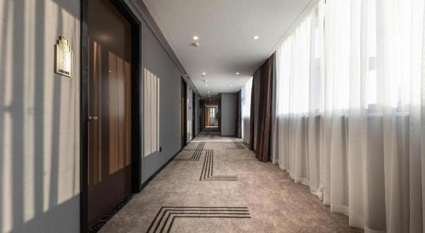 a hallway of a building with windows and a long corridor at Jinjiang Metropolo Haikou East High Speed Railway Station Normal University in Haikou