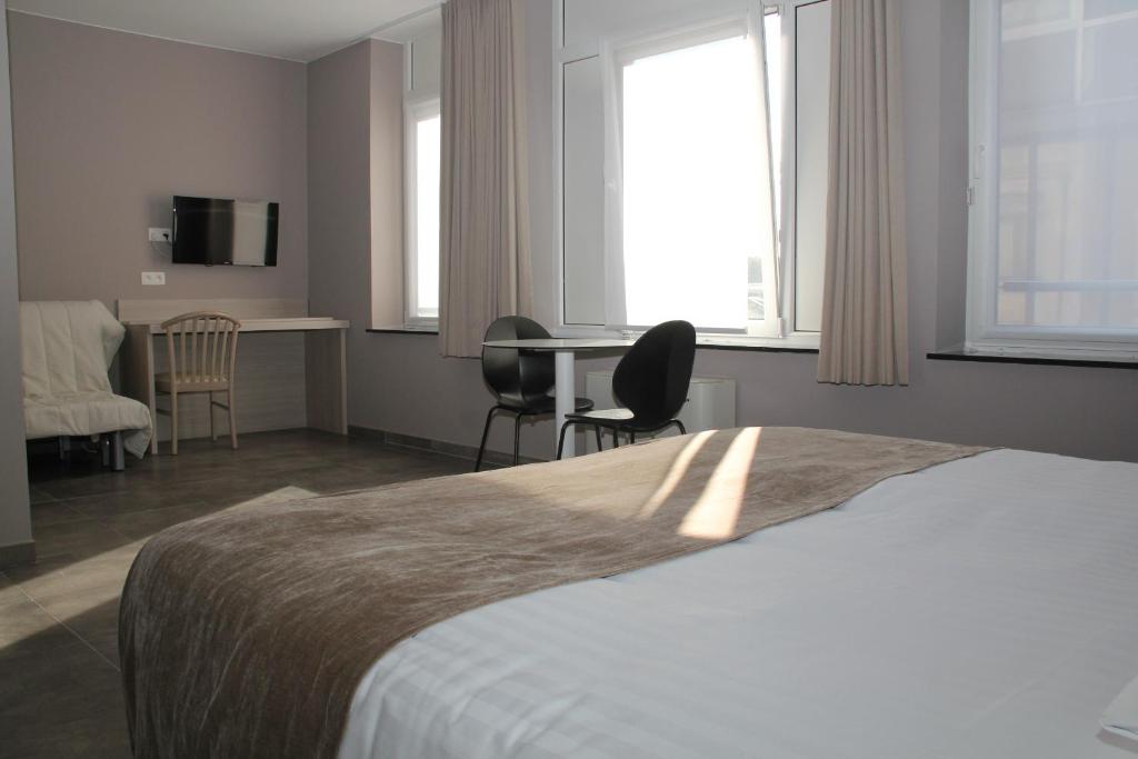 a bedroom with a bed and a table and chairs at Hotel La Louve in La Louvière