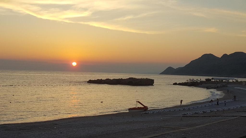 a beach with the sun setting over the water at Apartments Diva in Dobra Voda