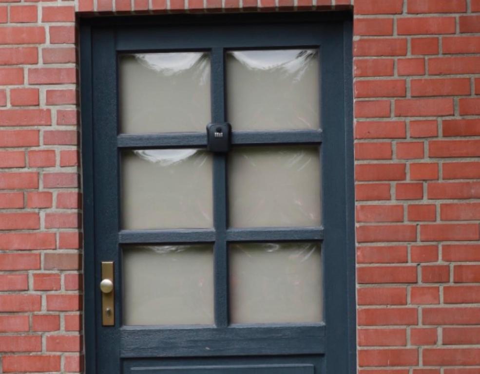 a black door with white curtains in a brick wall at Gemütliches Studio Ohlendorf in Seevetal