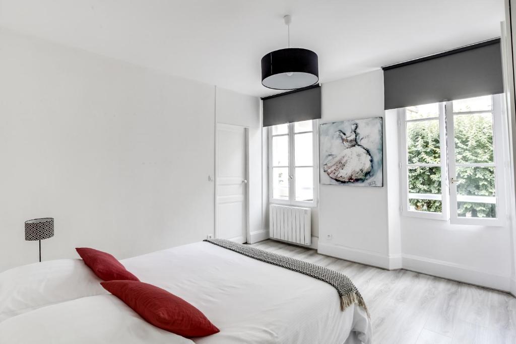 - une chambre blanche avec des oreillers rouges sur un lit dans l'établissement Fontainebleau Sweet Home, à Fontainebleau