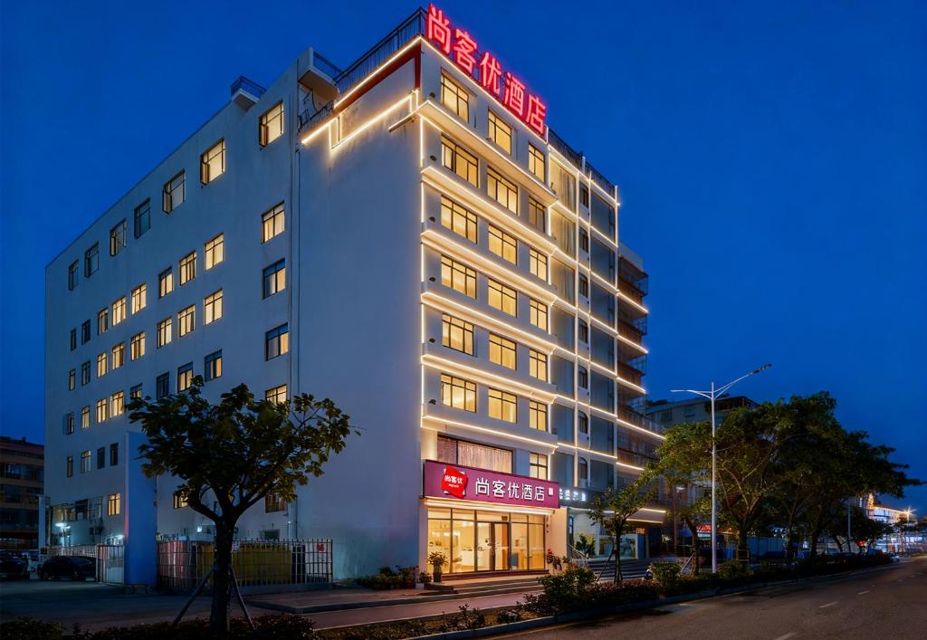 a white building with a red sign on it at Thank You Hotel Sanya Bay Coconut Dream Corridor Branch in Sanya