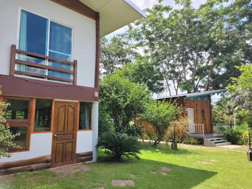 a house with a yard with grass and trees at Coco farm stay Suanphueng in Ratchaburi