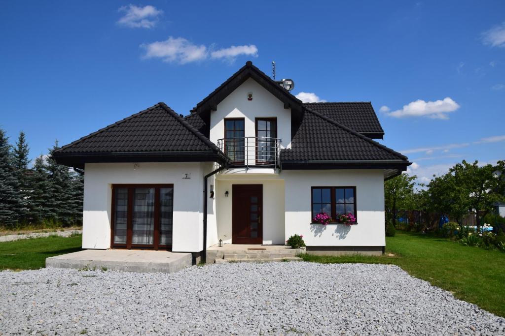 una casa blanca con techo negro en Cyprysowa 7, en Kiełczów