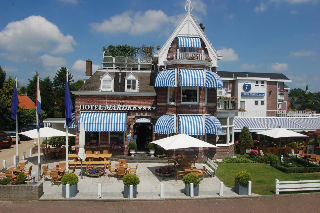 un hotel con mesas y sombrillas frente a un edificio en Fletcher Hotel Restaurant Marijke, en Bergen