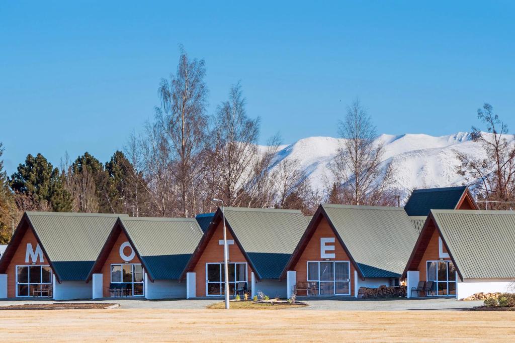 um grupo de casas com montanhas cobertas de neve ao fundo em Mountain Chalets Motel em Twizel