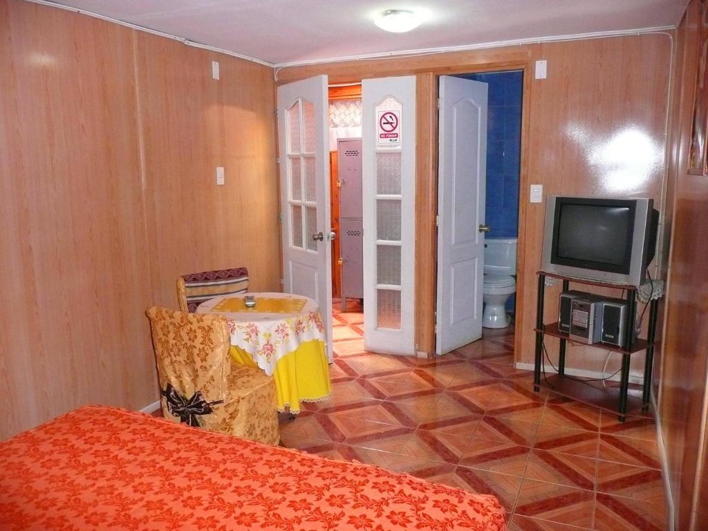 Zimmer mit einem Tisch, einem TV und einem Zimmer in der Unterkunft Hospedaje Glamour in Machalí