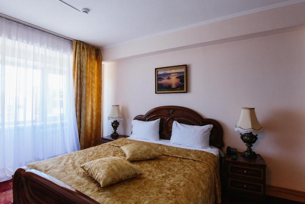1 dormitorio con 1 cama con 2 almohadas y ventana en Petropavlovsk Hotel en Petropávlovsk-Kamchatski