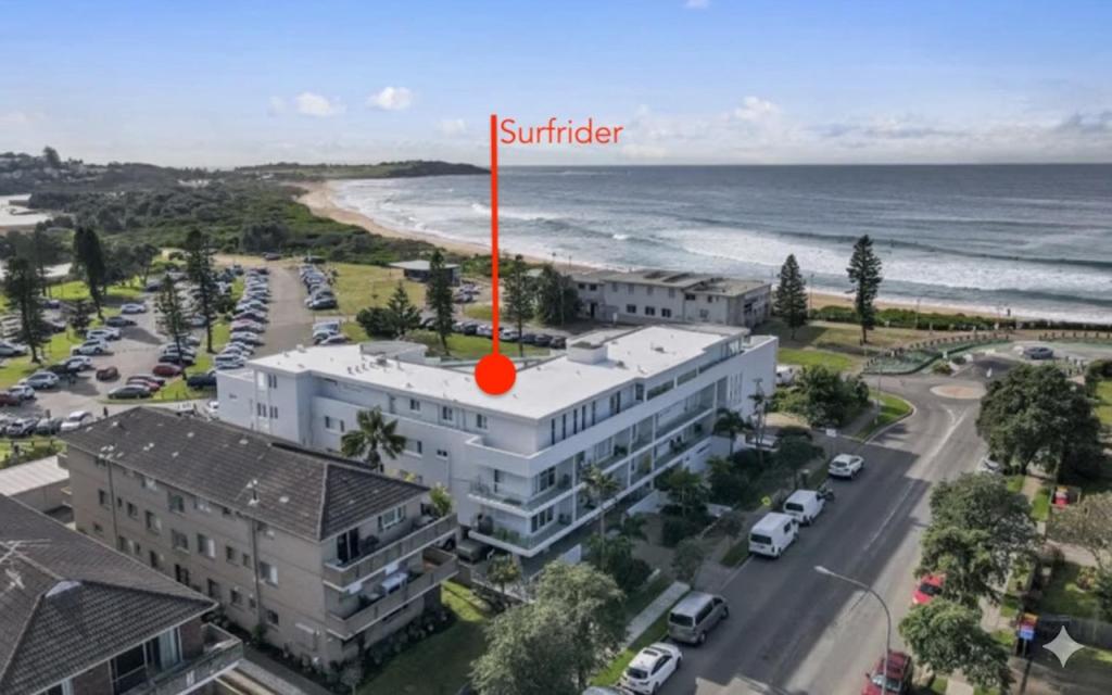 a building with a red spot on it next to the beach at Dee Why Beach - Surfrider Studio 8 in Deewhy