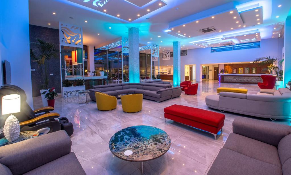 a lobby with couches and tables and a bar at Nicholas Color Hotel in Ayia Napa