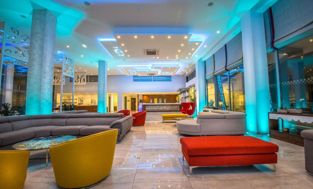 a lobby with couches and chairs in a building at Nicholas Color Hotel in Ayia Napa
