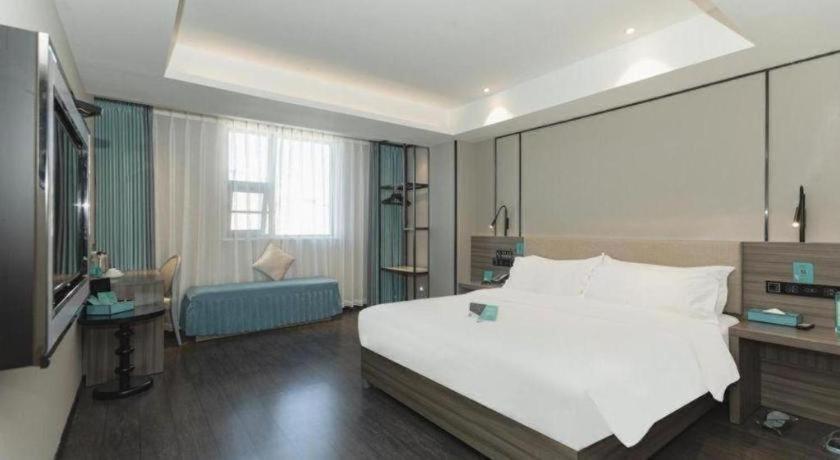 a bedroom with a large white bed and a television at Xana Lite Xichang Hangtian Avenue Branch in Xichang