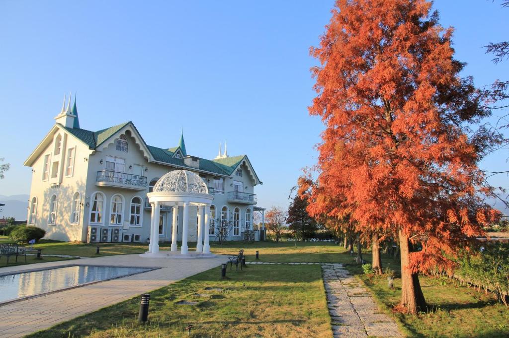 a large white house with a tree in the foreground at Sigma Castle in Yuanshan