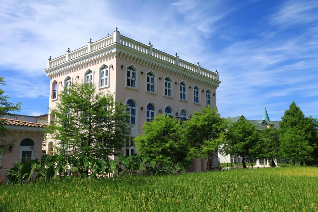 a large white building with a grass field in front of it at Sigma Castle in Yuanshan
