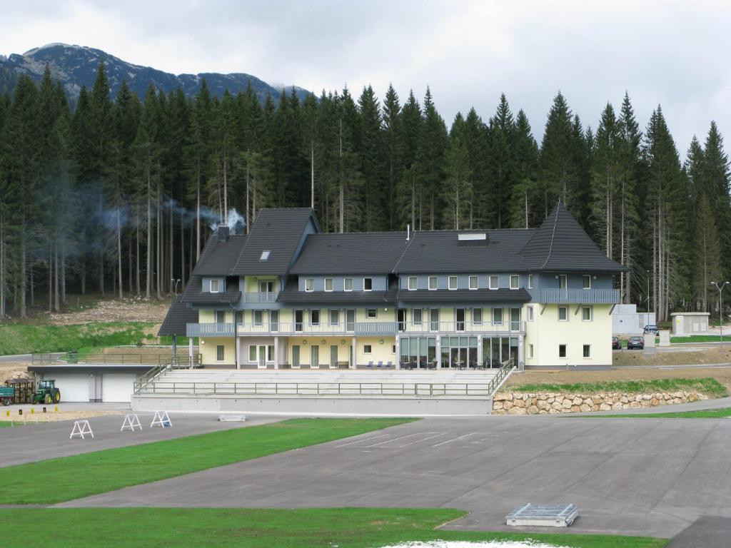 ein großes Gebäude mit schwarzem Dach auf einer Piste in der Unterkunft Hotel Center Pokljuka in Goreljek