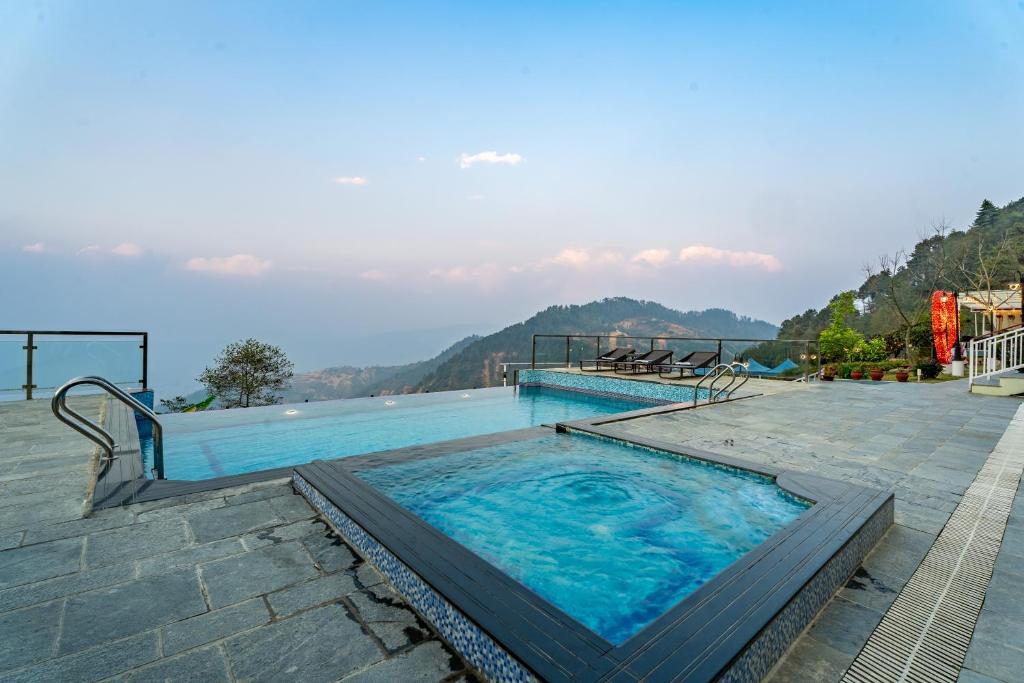 une piscine avec vue sur une montagne dans l'établissement Village Highland Resort, à Godāvari