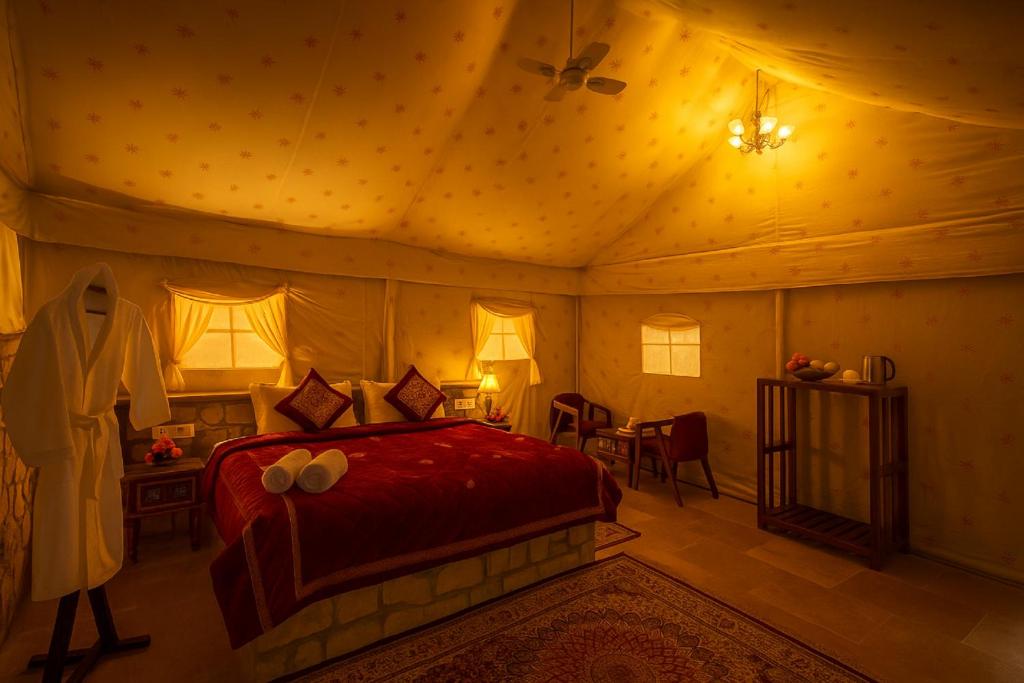 Un dormitorio con una cama roja en una habitación. en Desert Island Camp & Resort Jaisalmer, en Jaisalmer