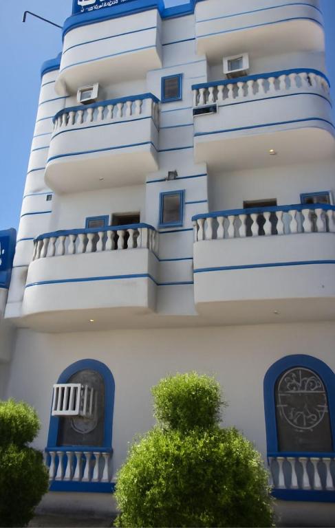 a tall white building with blue windows and balconies at فندق السعادة in Al Qarn