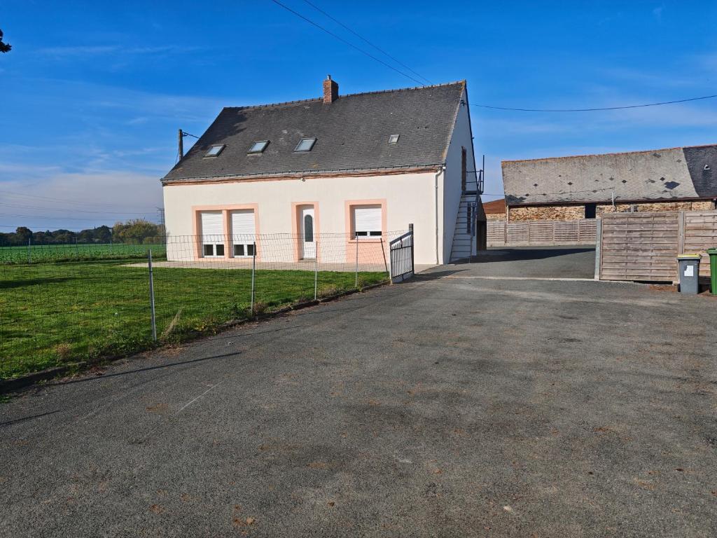 a white house with a fence next to a field at Le calme a proximité de la ville in Erbray
